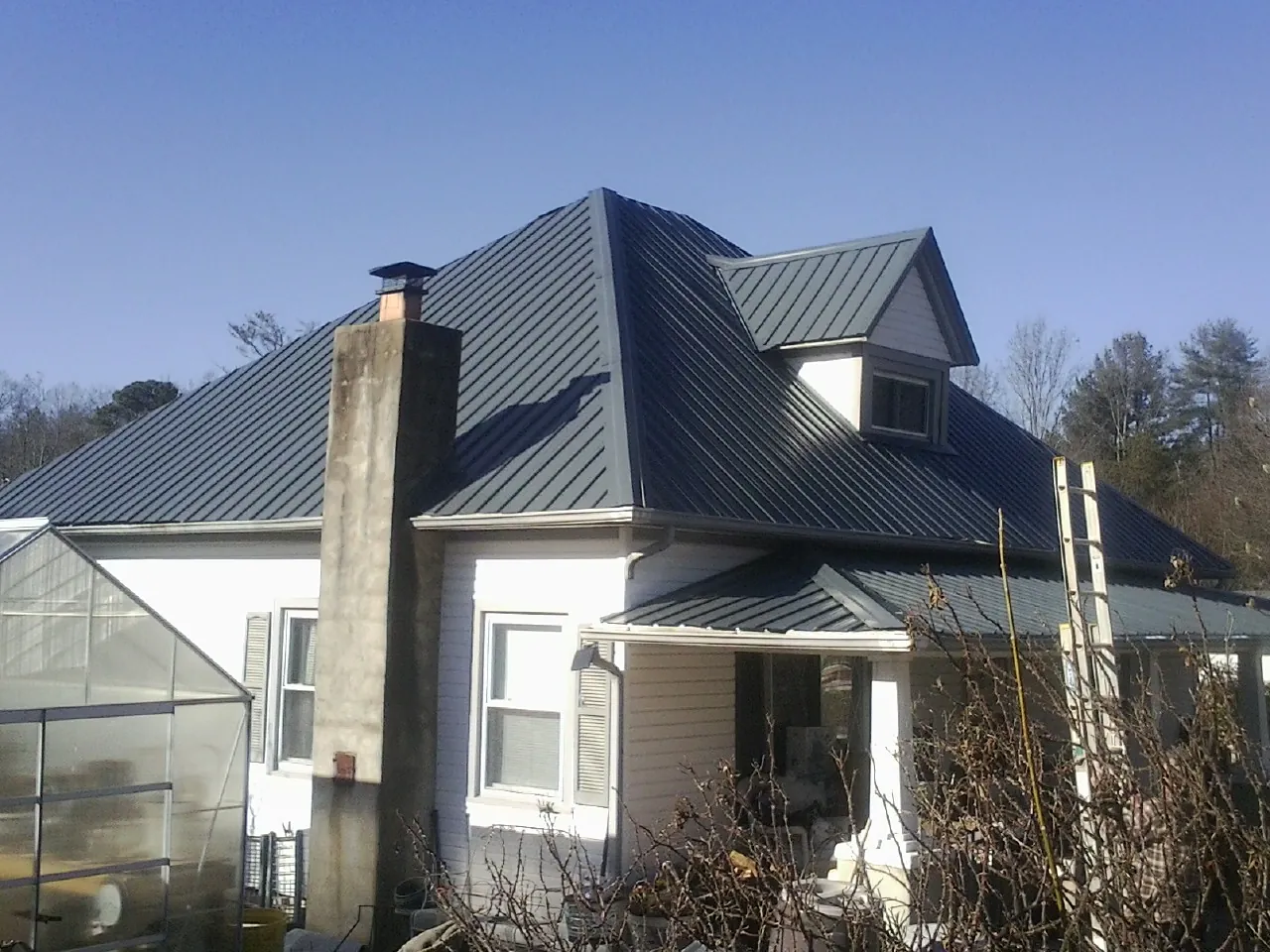 Dark blue standing seam metal roof on a white farmhouse with dormer — Slate & Tile Roof Repair by Roofing Brothers in Massillon