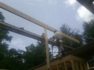 Carpenter setting a ridge beam over a new addition frame — Ice Dam Removal by Roofing Brothers in Massillon