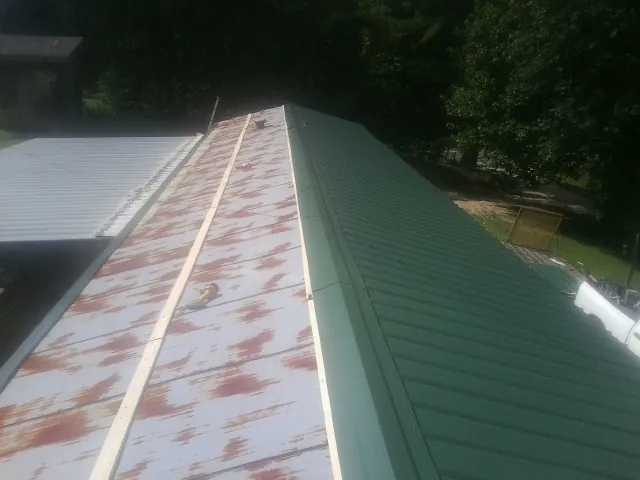 Old rusted panels beside newly installed green metal roofing — Wind Damage Roof Repair by Roofing Brothers in Massillon