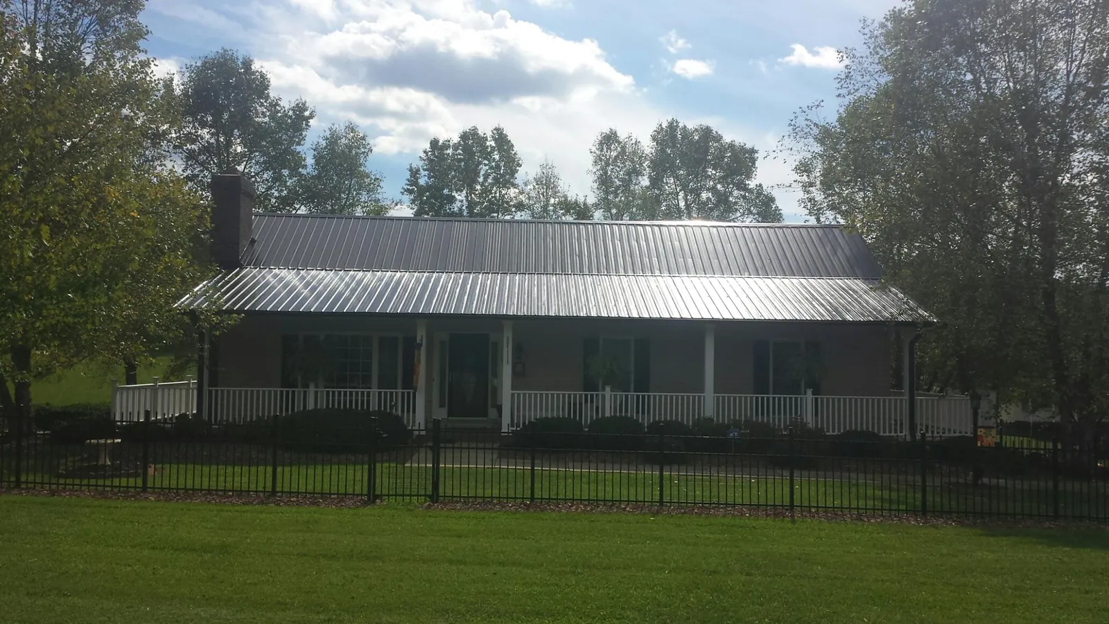 Gray metal roof on a brick ranch with a full width front porch — Gutter Guard Installation work by our crew in Massillon