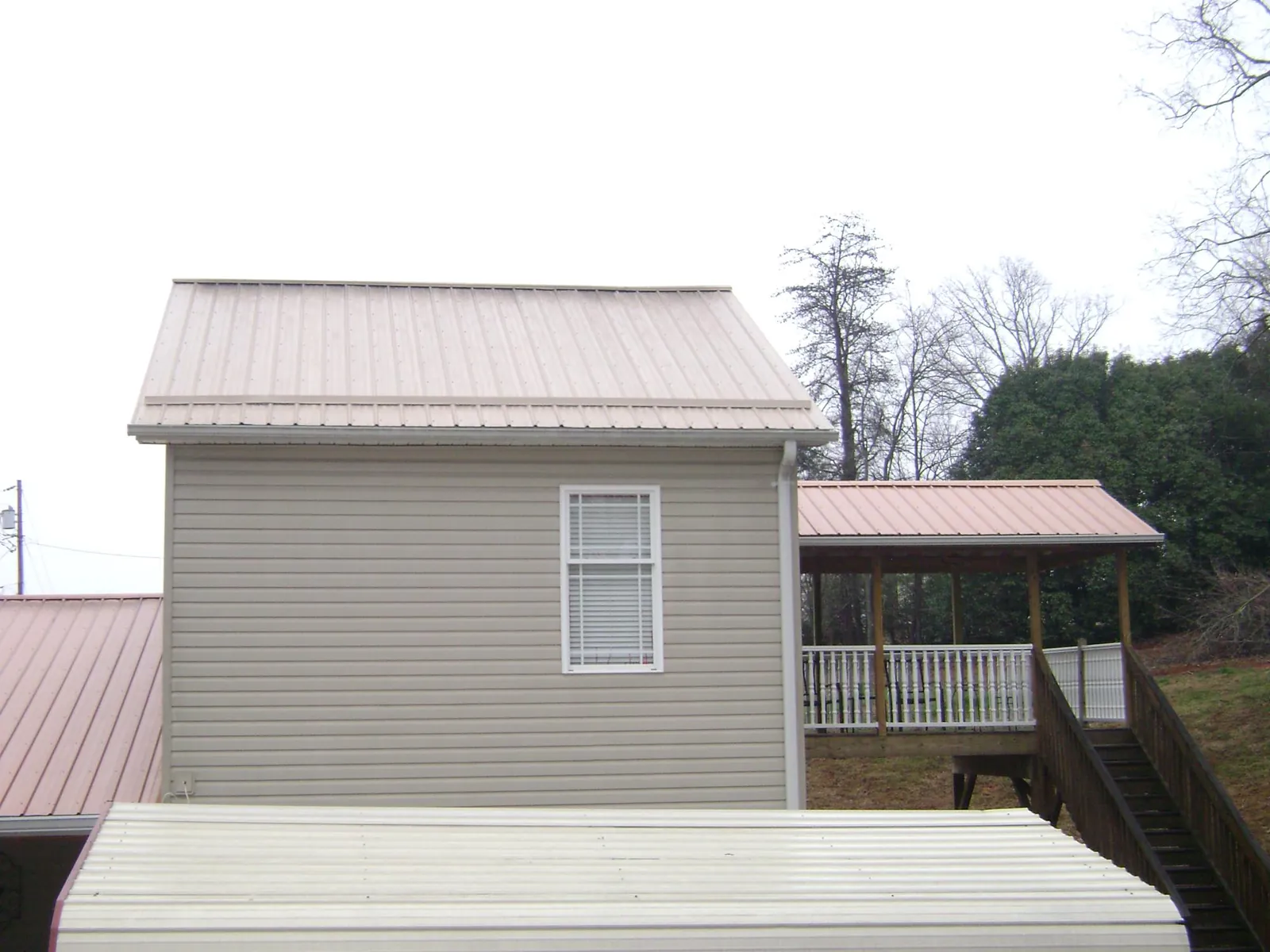 Tan metal roofs on a two story addition and attached porch, from a Roof Replacement job in Massillon