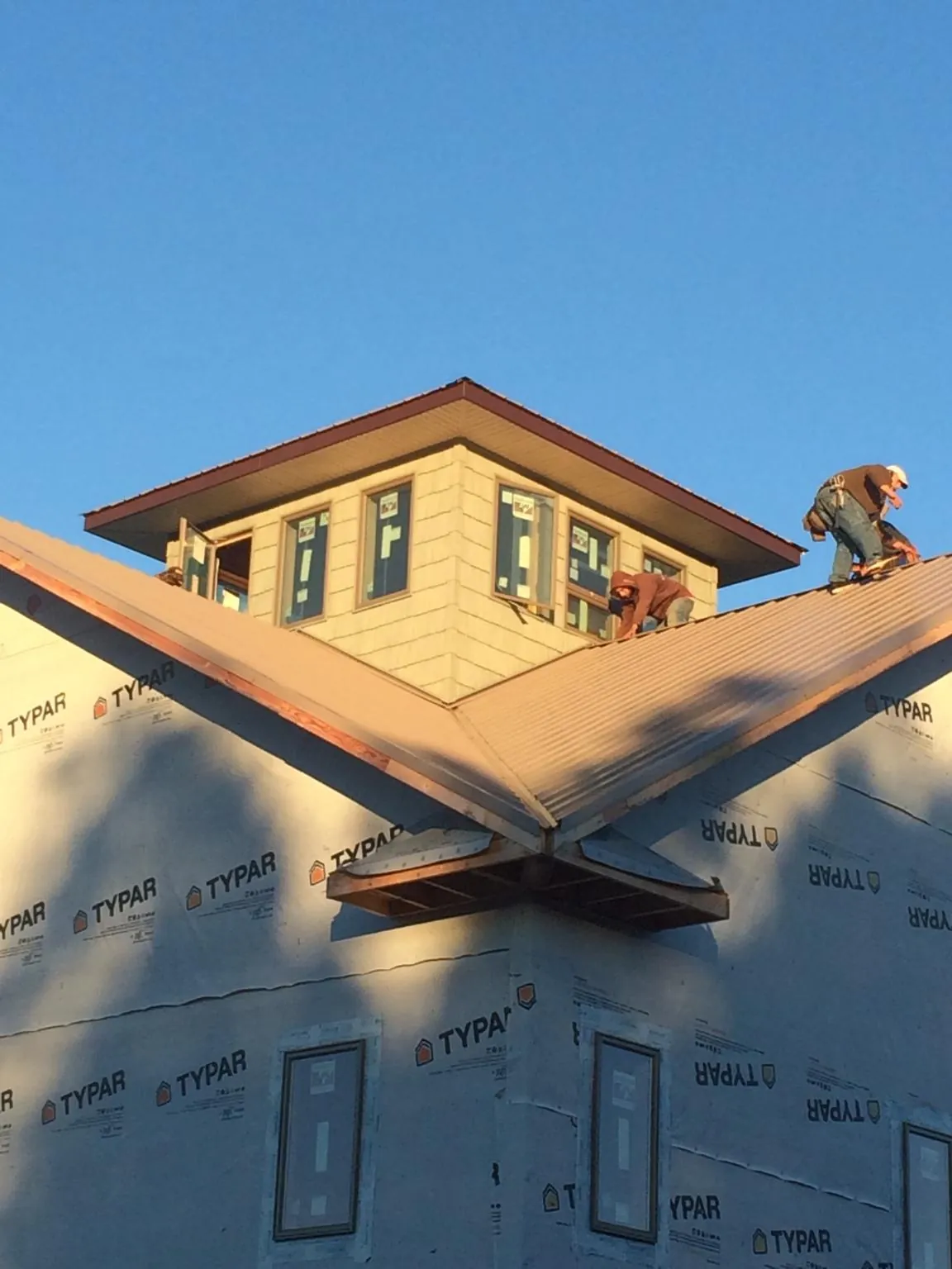 Roofers working around a rooftop cupola on a new metal roof at sunset — Roof Waterproofing in Massillon by Roofing Brothers
